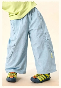 Detail view of light blue wide-leg kids pants with yellow Smile print and elastic waist