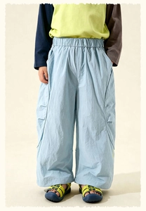 Detail of light blue wide-leg boys' trousers with elastic waistband and pleated pockets