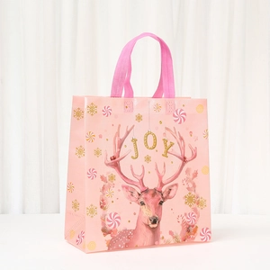 Detailed view of pink Christmas non-woven gift bag with reindeer and joy pattern