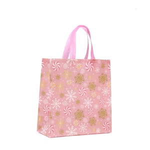 Pink non-woven Christmas gift bag with festive white snowflakes and candy patterns