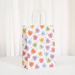 Geschenktüte aus weißem Papier mit bunten Herzmotiven und weißen Kordelgriffen