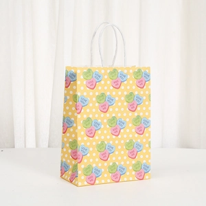 Gelbe Geschenktüte aus Kraftpapier mit bunten Herzbonbons und weißen Papiergriffen