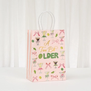 Pink paper gift bag with A Tini Bit Older cocktail print and white woven handles