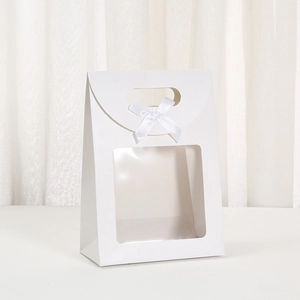 Detailed view of white paper gift bag with square window and elegant white silk bow