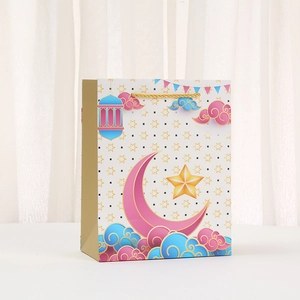 Detail of white gift bag with golden crescent moon, stars, and woven handle for Ramadan
