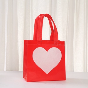 Detail of red non-woven tote bag with white heart print and sturdy webbing handles