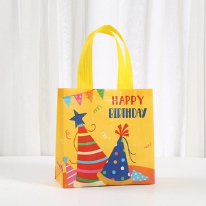 Detail of yellow non-woven birthday gift bag with happy birthday print and party motifs