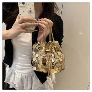 Close-up of golden sequin bucket bag featuring metallic chain and pearl drawstring detail