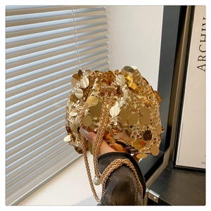 Close-up of golden sequin bucket bag featuring a drawstring closure and pearl chain strap