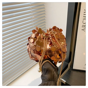 Detail of bronze sequin bucket bag with gold chain strap and elegant pearl charm