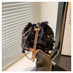 Close-up of black sequin bucket bag with gold chain strap and pearl details