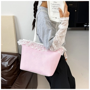 Detail of pink canvas tote bag featuring delicate white lace trim and letter embroidery