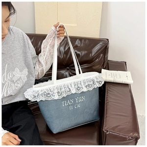 Detail of blue denim tote bag with white lace trim and heart embroidery accents