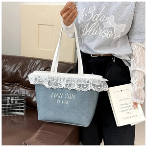 Close-up of light blue canvas tote bag with delicate white lace trim and embroidery