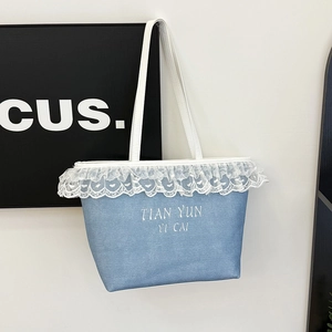 Blue denim tote bag with delicate white lace trim and minimalist shoulder strap design