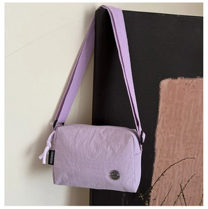 Detail of lavender nylon crossbody bag showing crinkled texture and silver M logo