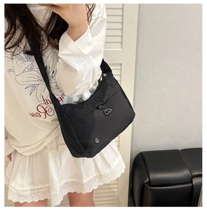 Detail of black nylon crescent shoulder bag with metallic logo and triangle zipper pull
