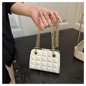 Détail de la texture en similicuir blanc matelassé avec des bandoulières chaîne dorée
