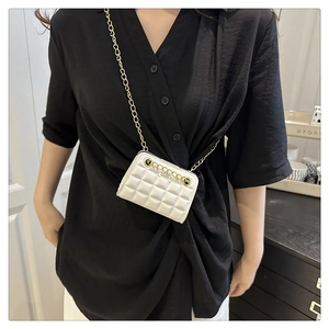 Gros plan d'un sac bandoulière blanc matelassé avec une chaîne dorée sur une chemise
