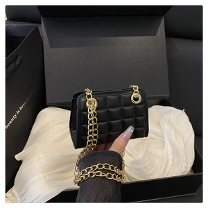 Gros plan sur le mini sac matelassé noir avec chaîne dorée sur boîte cadeau en satin