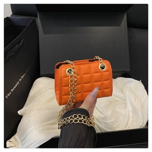 Détail du mini sac bandoulière matelassé orange vif avec chaîne dorée sur emballage cadeau