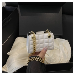 Gros plan du mini sac blanc matelassé avec chaîne dorée tenu à la main pour l'échelle