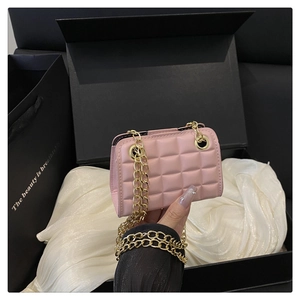 Détail de sac matelassé rose avec motif diamant brillant et bandoulière en chaîne dorée
