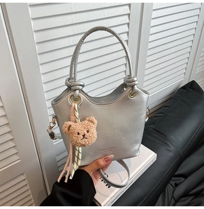 Silver bucket bag with leather texture and cute brown plush bear charm detail