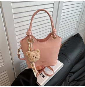 Pink leather bucket bag detail with a knotted handle and brown plush bear charm