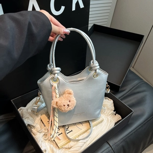 Silver bucket bag with teddy bear charm and striped tassel shown from a front angle