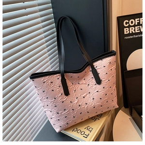 Nahaufnahme der rosa Plissee-Tasche mit schwarzen Schleifen und Ledergriffen