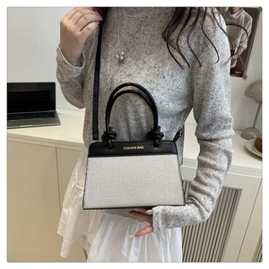 Detail of minimalist black and cream patchwork tote bag with gold lettering shown on model