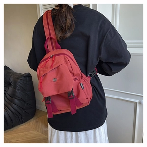 Détail du sac à dos en nylon rouge imperméable montrant la poche latérale et la boucle