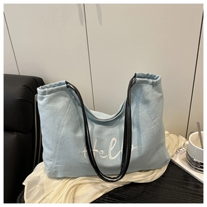 Détail du sac fourre-tout en toile bleu clair avec broderie Hello et anses en cuir