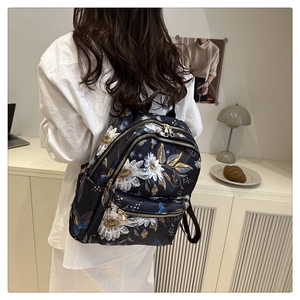 Detail showing the floral print nylon backpack with multiple gold zippers and compartments