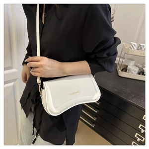 Detailed shot of white leather crossbody bag with gold Fashion & Bags lettering on black shirt