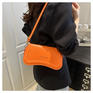 Close-up of vibrant orange crossbody bag with a unique curved base and fashion logo