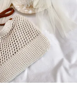 Dettaglio borsa tote in paglia intrecciata beige con trama all'uncinetto e manici in cuoio