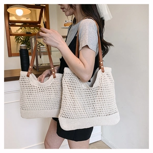 Detail of woven beach tote bag with brown leather straps and metal rivets in two sizes