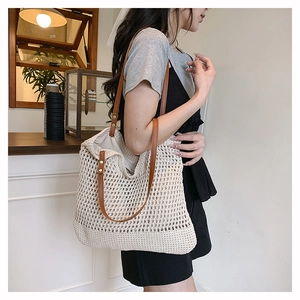 Detail of off-white crochet tote bag with brown straps and hollow woven pattern