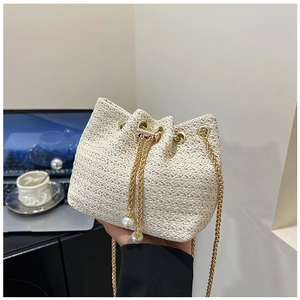 Detail of woven bucket bag featuring pearl drawstring and gold metal chain strap