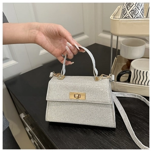 Détail du mini sac à main pailleté argenté avec fermoir doré et forme trapèze élégante