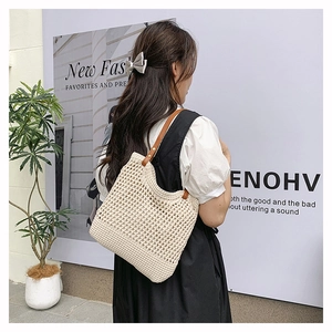 Close-up of hollow woven tote bag with brown leather handles and metal rivet details