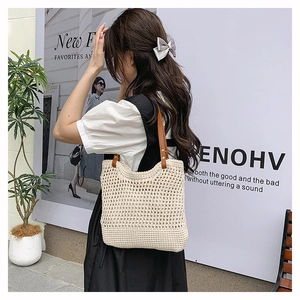 Detail of hollow woven tote bag with brown leather handles and metallic rivet accents