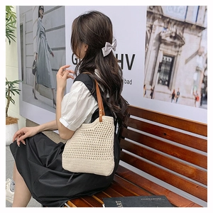 Detail of hollow woven shoulder bag with brown leather straps in a bohemian style
