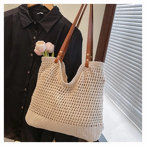 Close-up of hollow woven beach bag with brown leather straps and metal rivets detail