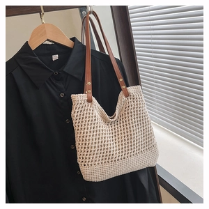 Detailed close-up of woven cream knit tote bag featuring faux leather straps and gold rivets