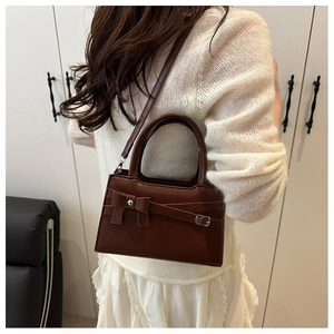 Detail of vintage brown leather handbag with elegant bow design and crossbody strap