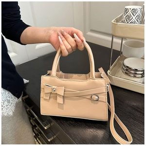Beige tote bag with bow detail and leather strap shown in a lifestyle setting