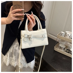Close-up of a cream bow handbag featuring a metal buckle and high-quality PU leather